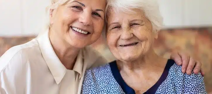 Smiling elderly woman with a caregiver providing compassionate respite care at home in Ireland.